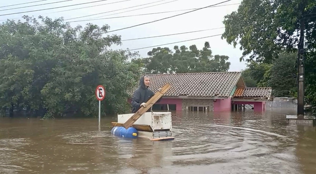 Jovem usa geladeira com galões como barco para resgatar animais de inundações em Canoas, no Rio Grande do Sul