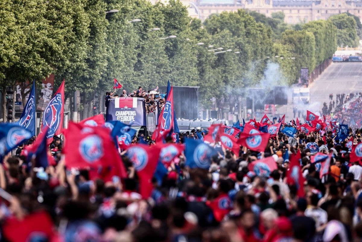 Paris Saint-Germain's supporters wave as the PSG team bus parades on the Champs-Elysees avenue in Paris on June 1, 2025, a day after PSG won the 2025 UEFA Champions League final football match against Inter Milan in Munich. (Photo by Thibaud MORITZ / AFP)