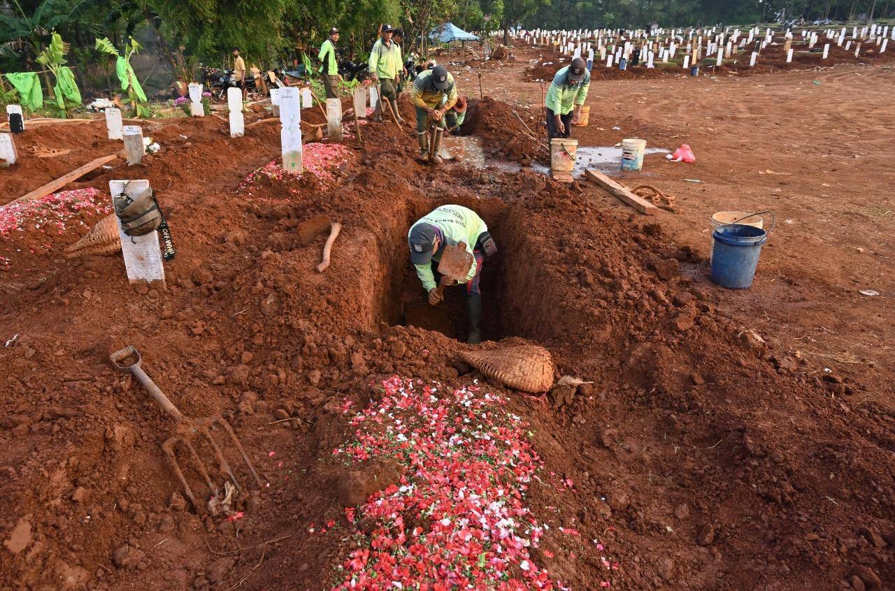 Em Jacarta na Indonésia, coveiros trabalham durante um funeral para vítimas do coronavírus no cemitério Pondok Ranggon