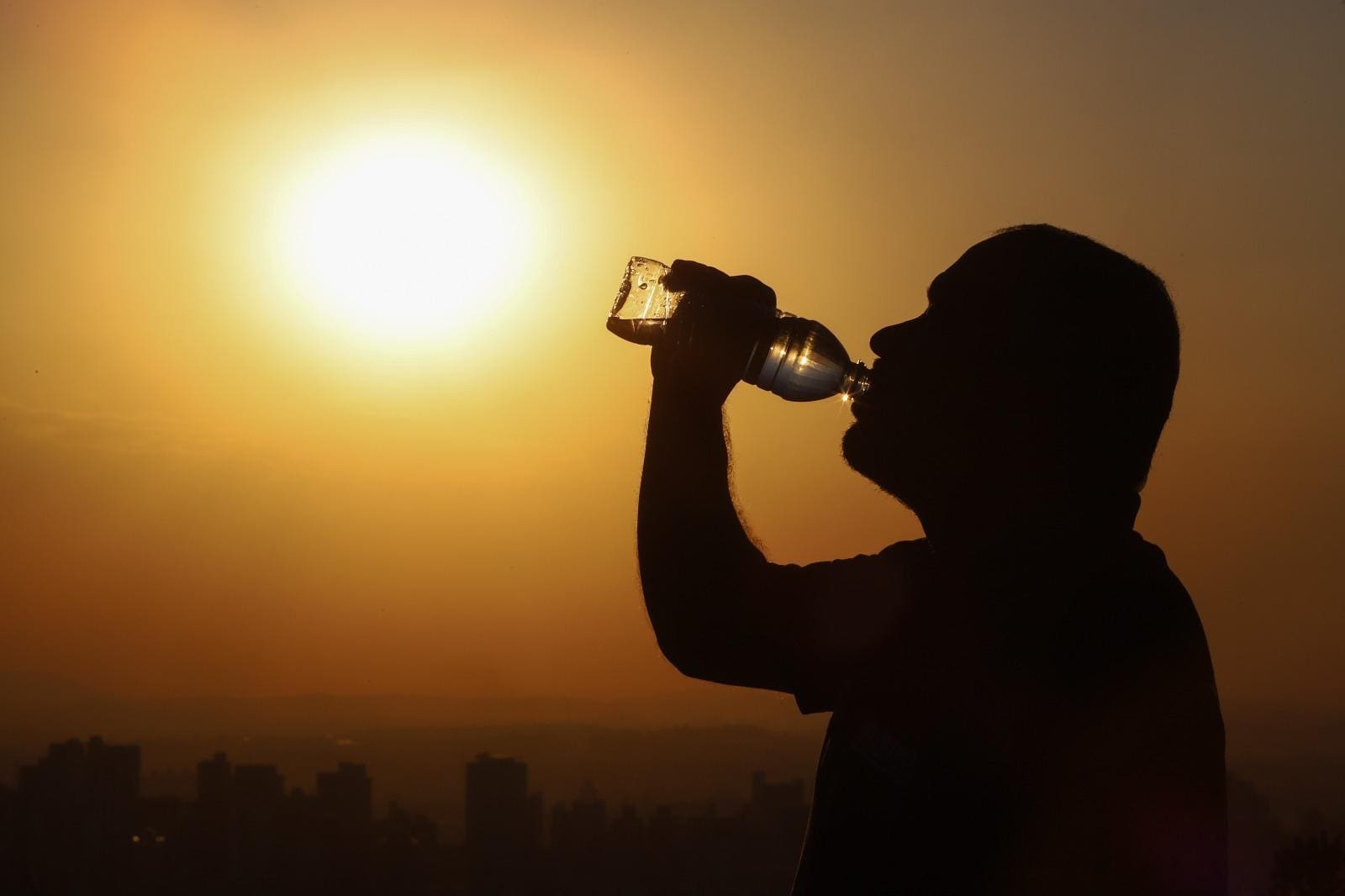 Imagem ilustrativa de calor. Homem se refresca bebendo água em um dia com baixa umidade.