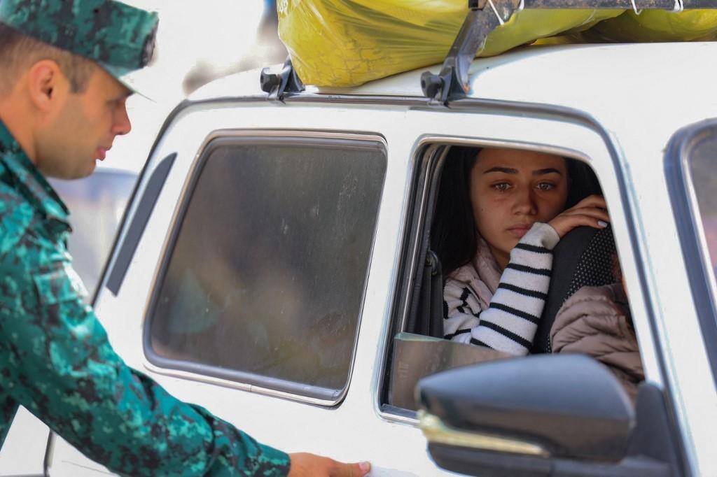 Um soldado do Azerbaijão controla um carro enquanto refugiados esperam em seu carro para cruzar a fronteira,