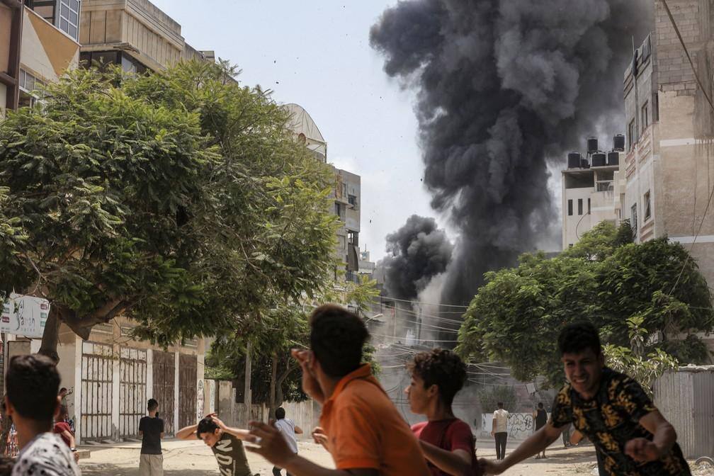 Pessoas correm para se proteger durante o bombardeio aéreo israelense na Cidade de Gaza em 6 de agosto de 2022