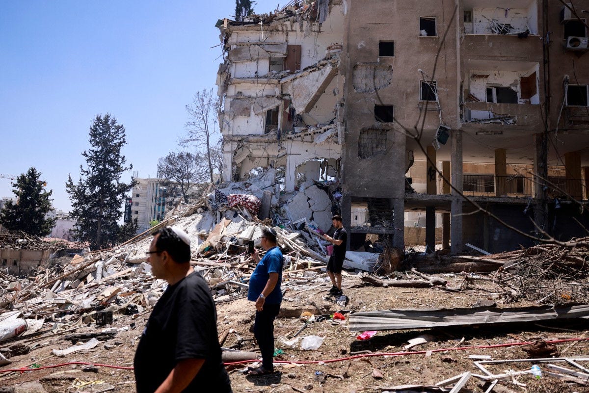 Residentes verificam a destruição após um ataque noturno com mísseis iranianos em Rohovot, no centro de Israel, em 15 de junho de 2025. O Irã atacou Israel na manhã de 15 de junho, com barragens de mísseis após um ataque massivo ter como alvo as instalações nucleares, militares e petrolíferas da república islâmica, e matado vários generais importantes.
