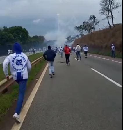 Integrantes de torcida organizada do Cruzeiro correm em direção ao ônibus da torcida do Palmeiras