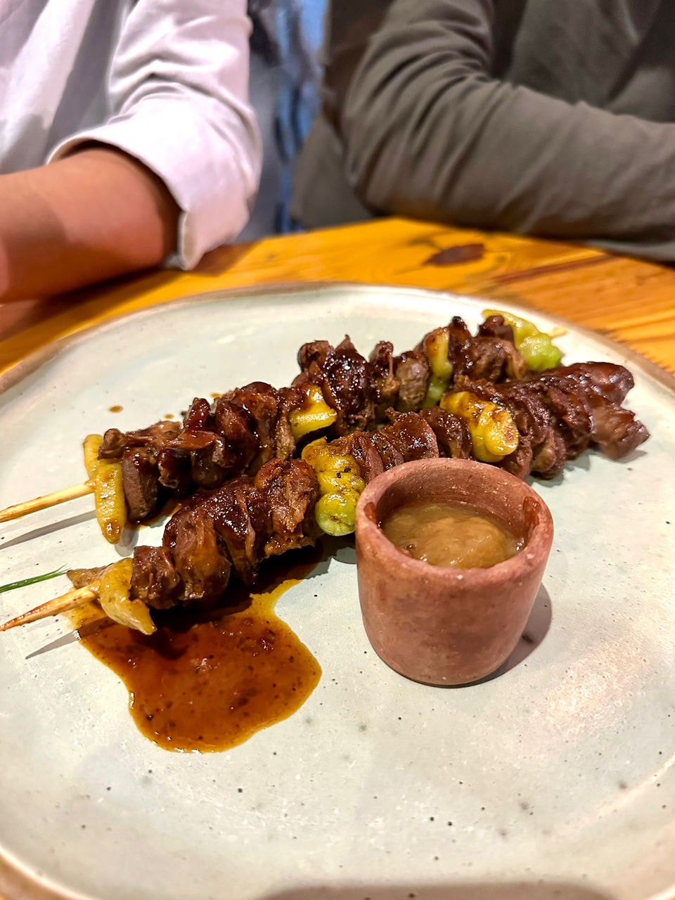 Espetinho de moela com picles de pimenta-de-cheiro e mel de alho assado.
