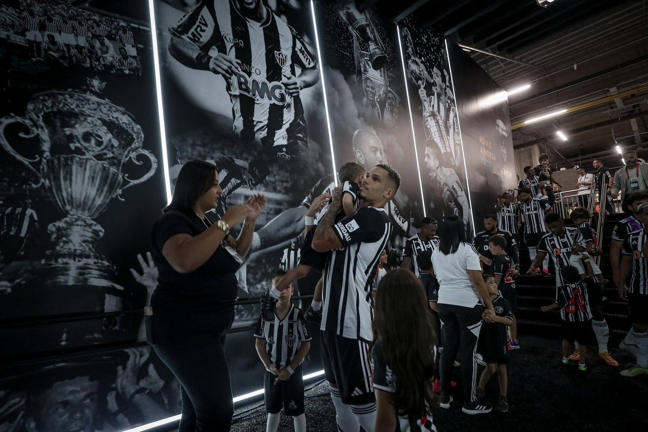 Paulinho e demais jogadores do Atlético passam por túnel na área interna do estádio todo decorado com fotos de momentos importantes do clube