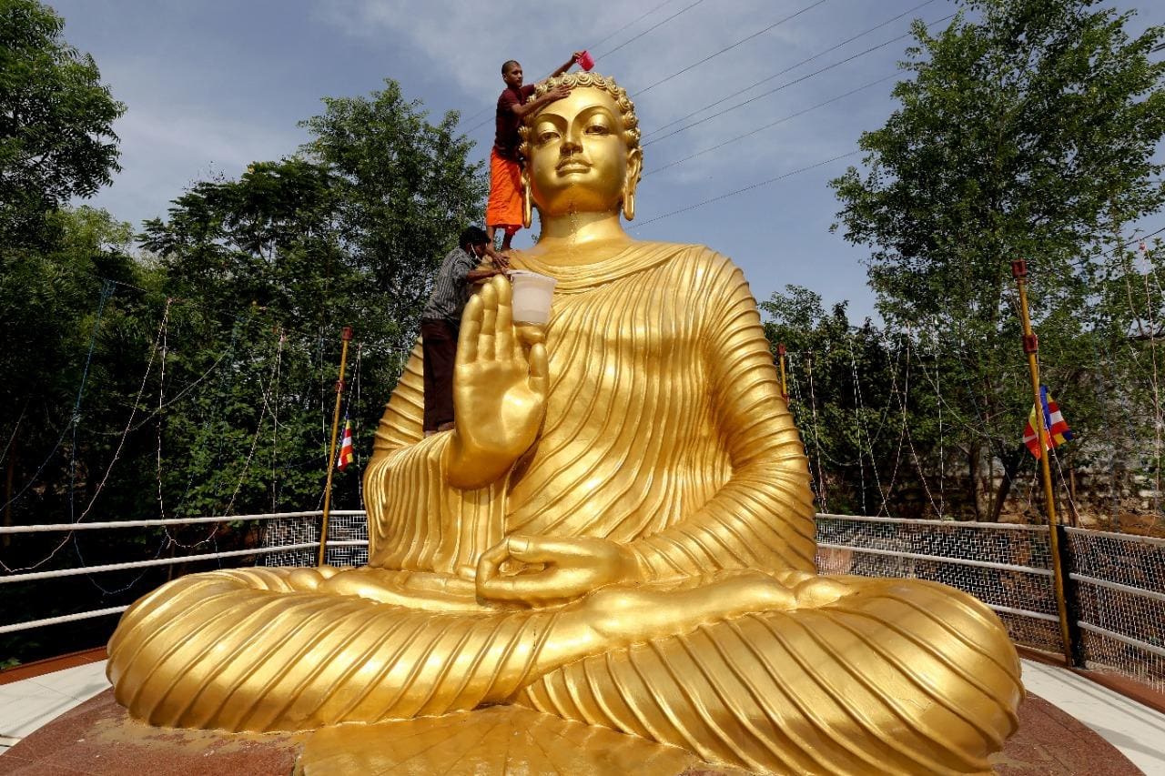 Monges limpam e decoram a estátua gigante de Buda para a celebração do de Vesak, em Bhopal