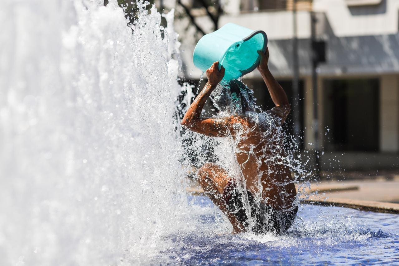 Homem se refresca na fonte da Praça da Savassi