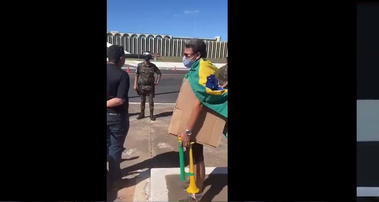 Manifestantes protestam em frente ao QG do Exército enquanto são observados por soldado