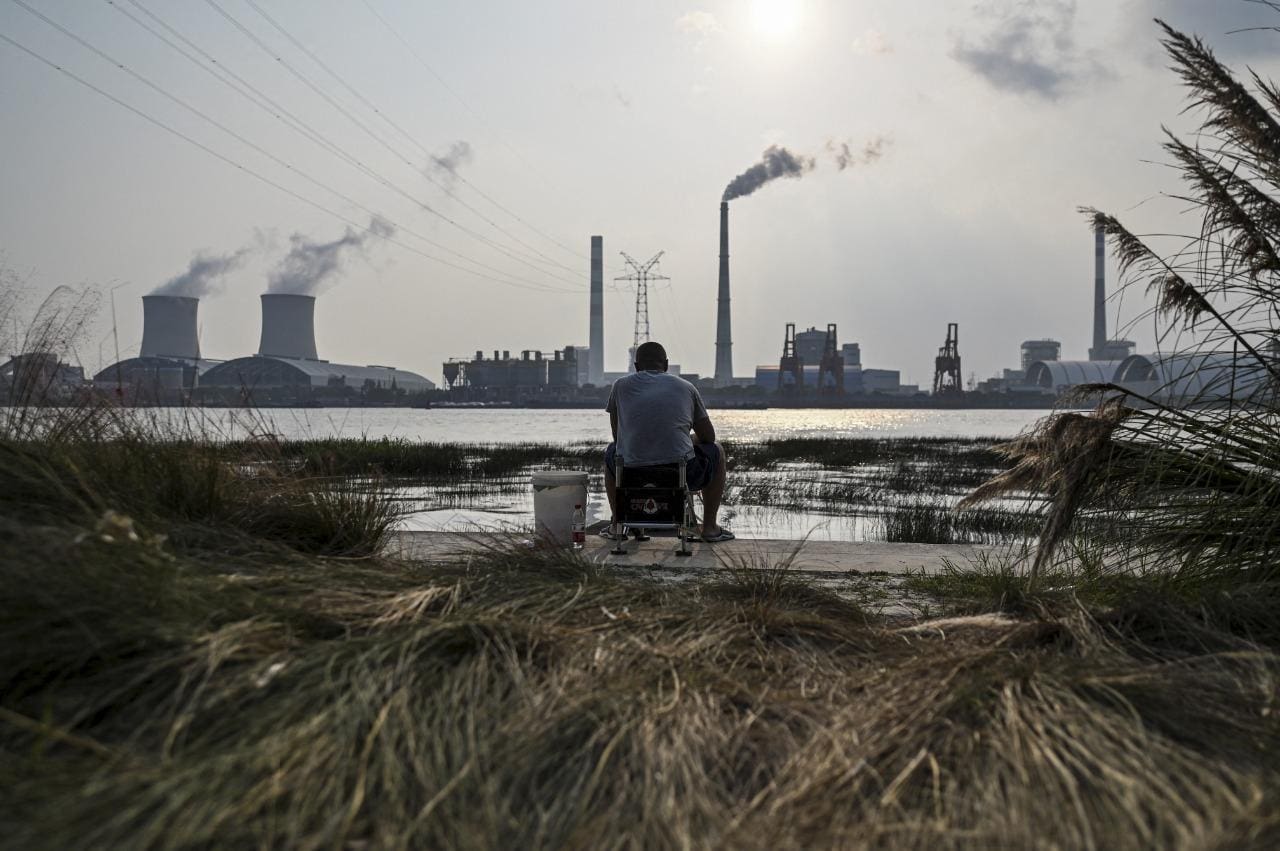 Homem pesca ao longo do rio Huangpu, do outro lado da Usina Elétrica de Carvão Wujing, em Xangai