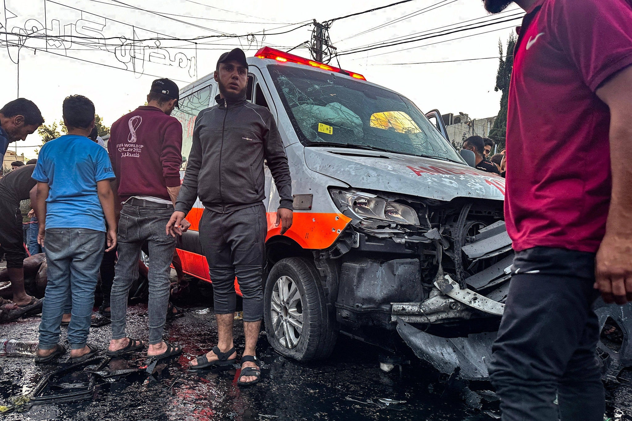 Pessoas se reúnem em torno de uma ambulância danificada em um suposto ataque israelense em frente ao hospital Al-Shifa, na cidade de Gaza