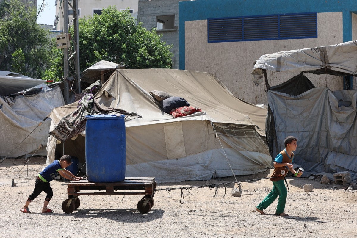 Meninos palestinos transportam um contêiner de plástico no bairro de Sheikh Radwan, na Cidade de Gaza,