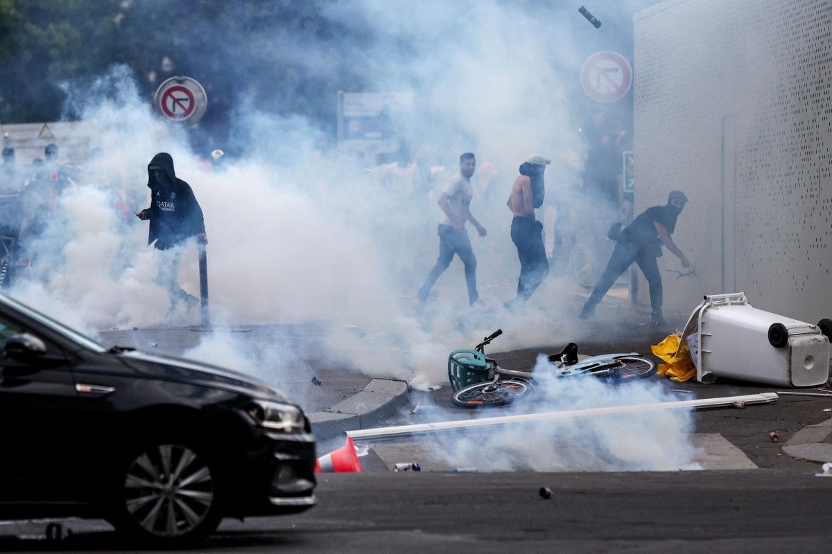 Individuals clash with police officers following the PSG team bus parade, near the Champs-Elysees avenue in Paris on June 1, 2025, a day after PSG won the 2025 UEFA Champions League final football match against Inter Milan in Munich. (Photo by Romain PERROCHEAU / AFP)