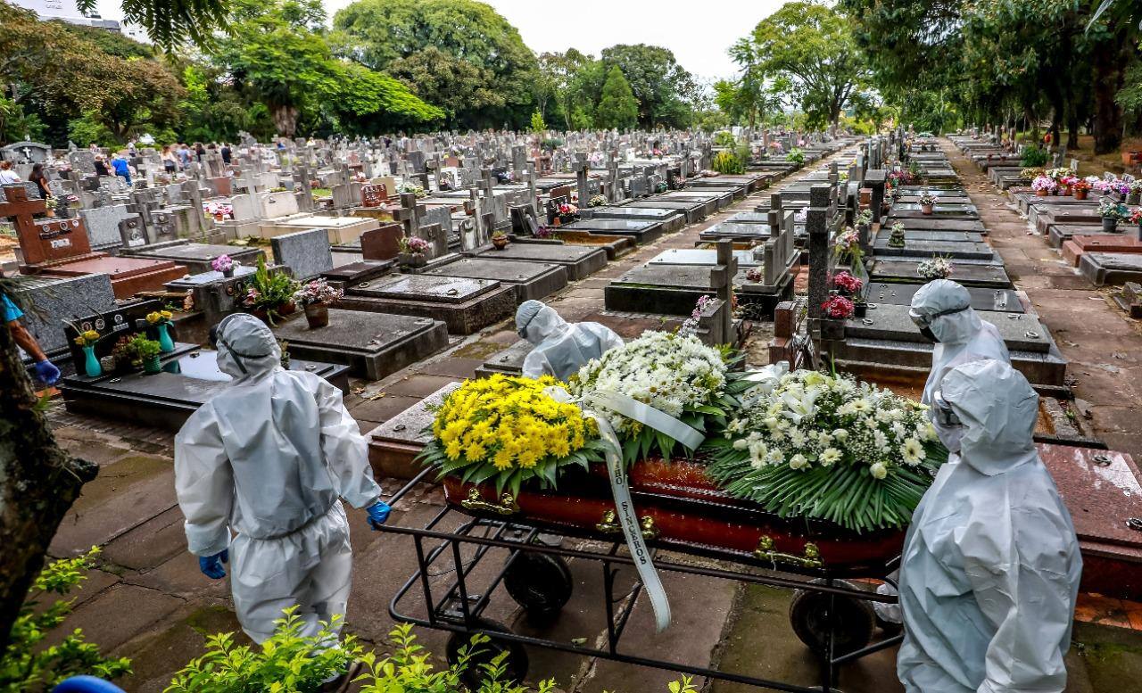 Trabalhadores do cemitério São João em Porto Alegre carregam um caixão durante o enterro de mais uma vítima de covid-19