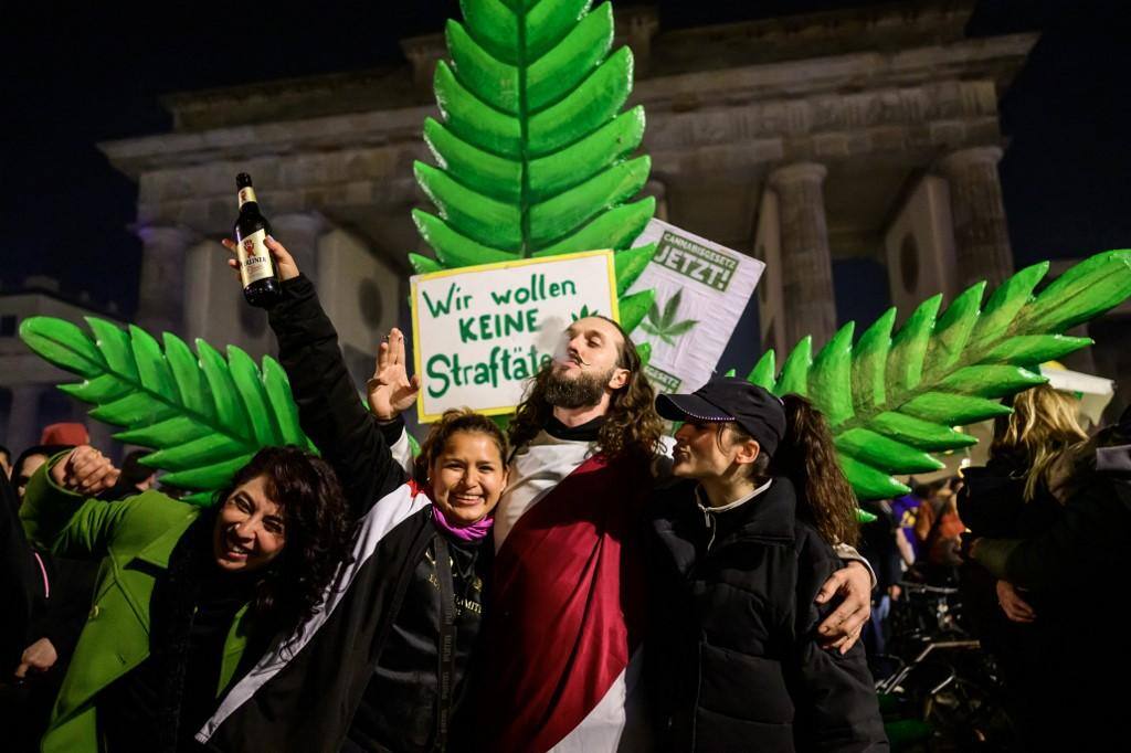Pessoas comemoram em frente a uma planta gigante de maconha em uma manifestação do lado de fora do Portão de Brandemburgo, em Berlim