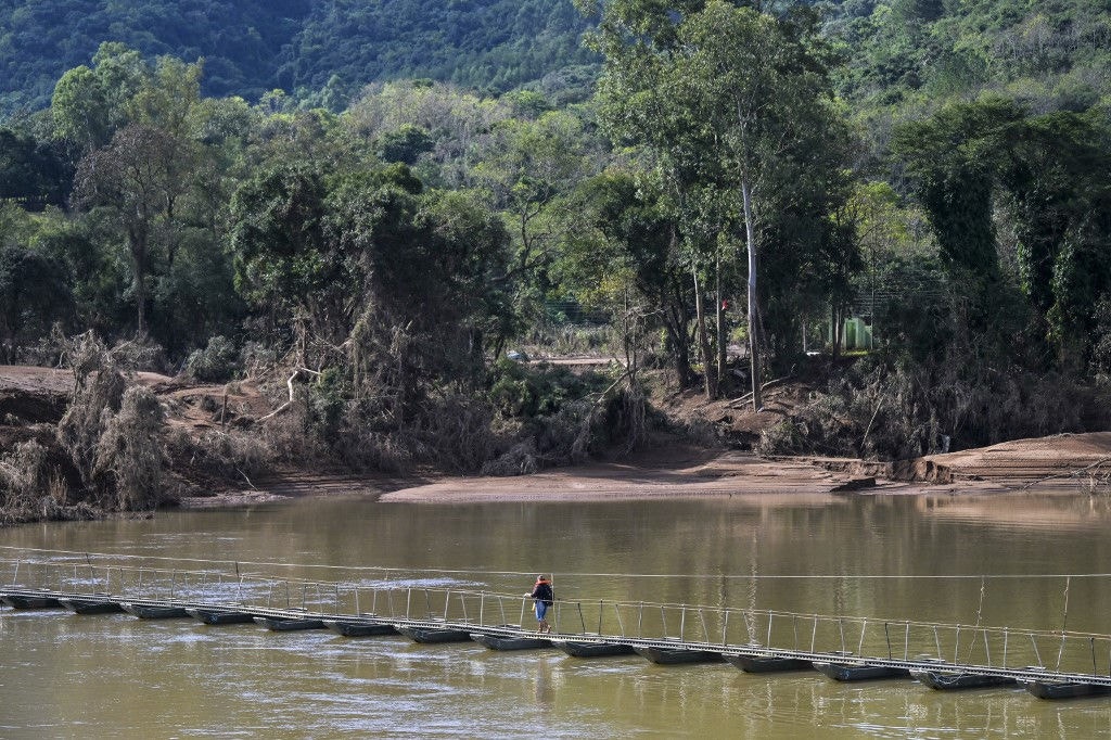 Mulher atravessa passarela flutuante que havia sido instalada pelo Exército no rio Forqueta