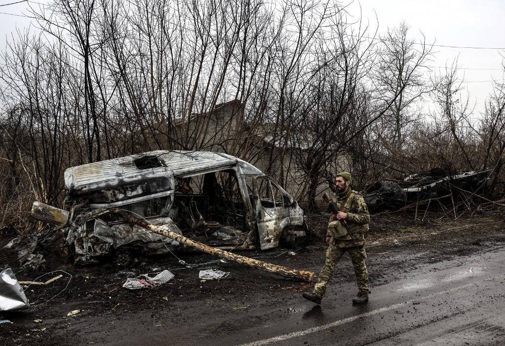 Um soldado ucraniano patrulha ao lado de um veículo queimado na vila de Lukianivka, perto de Kiev, em 30 de março de 2022.
