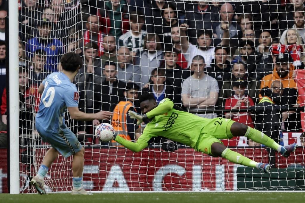 O goleiro camaronês nº 24 do Manchester United, Andre Onana (R), defende um pênalti do meio-campista inglês nº 10 do Coventry City, Callum O'Hare