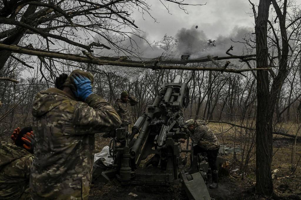 Artilheiro ucraniano tapa os ouvidos a disparar um obuseiro ocidental M177 contra posições russas em Bakhmut