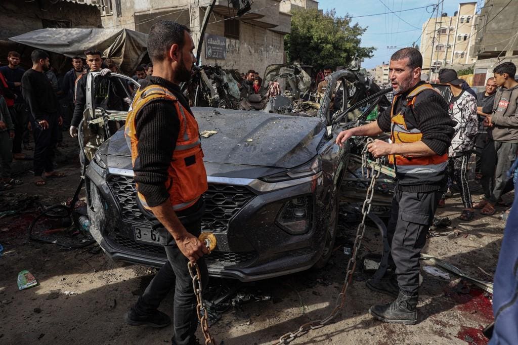 Membros da defesa civil palestina trabalham perto de um carro após o suposto bombardeio israelense em Rafah, no sul da Faixa de Gaza