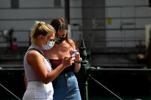 Duas mulheres jovens em máscaras caminham ao longo de um tranquilo cais circular em Sydney