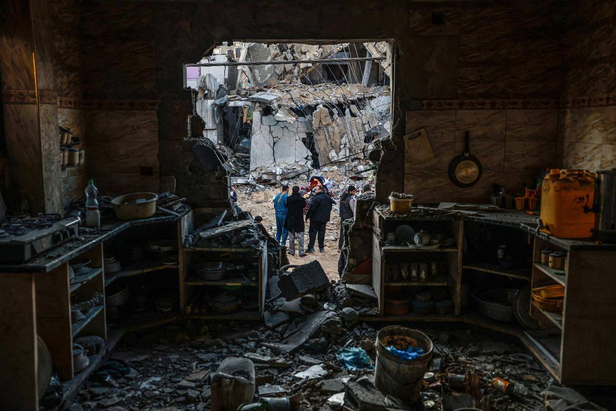 Pessoas verificam os danos após o bombardeio israelense em Rafah, no sul da Faixa de Gaza, em 3 de fevereiro de 2024, enquanto os combates continuam entre Israel e o grupo palestino Hamas