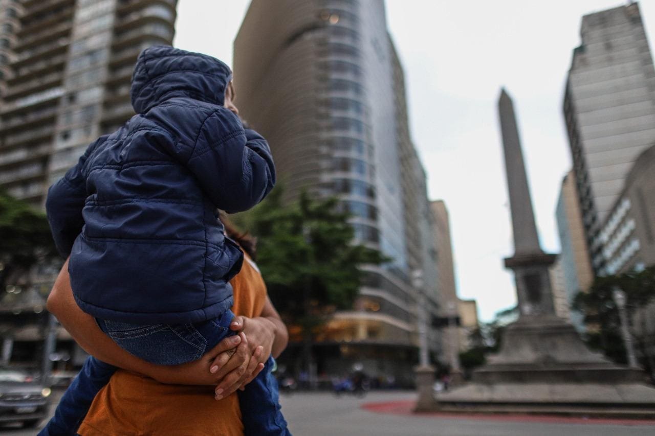Imagem mostra mulher carregando criança agasalhada no centro de Belo Horizonte