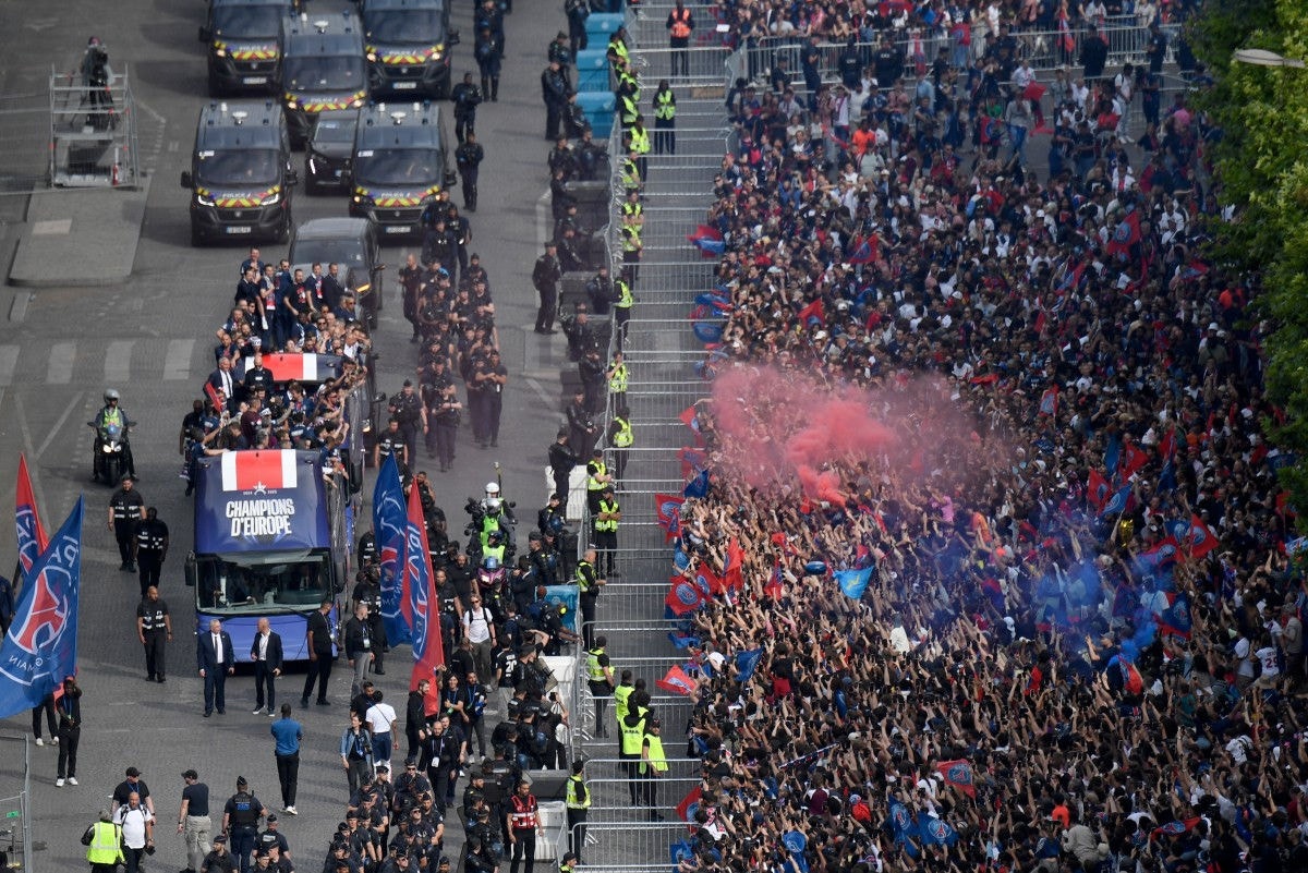 Torcedores do Paris Saint-Germain acenam enquanto o ônibus da equipe do PSG desfila na avenida Champs-Élysées, em Paris