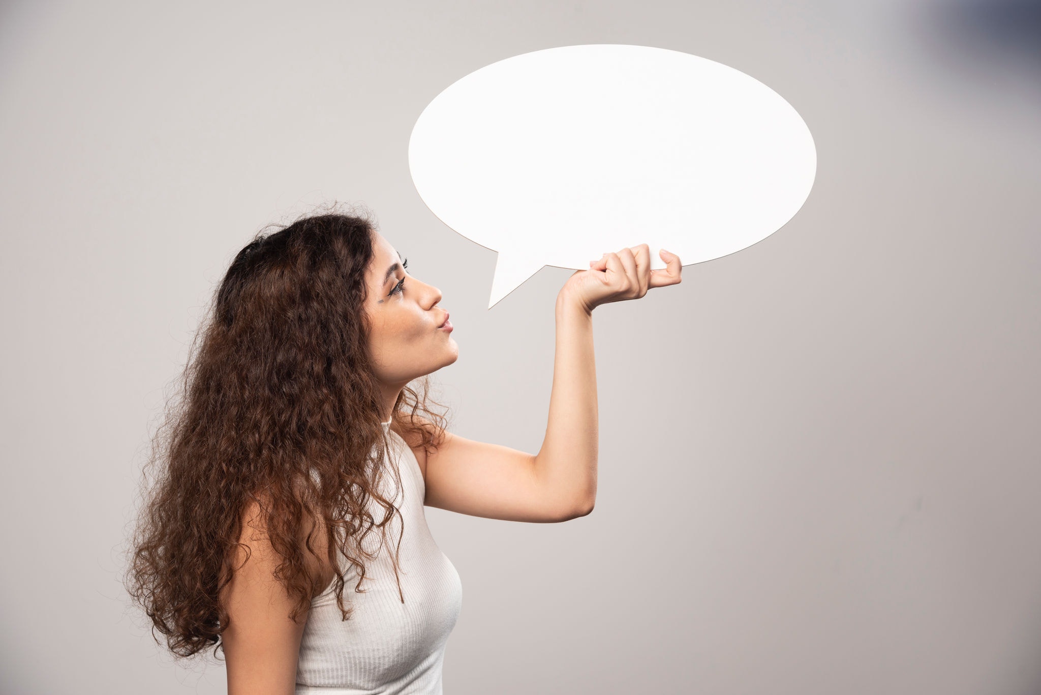 Young woman looking at blank white speech bubble. High quality photo