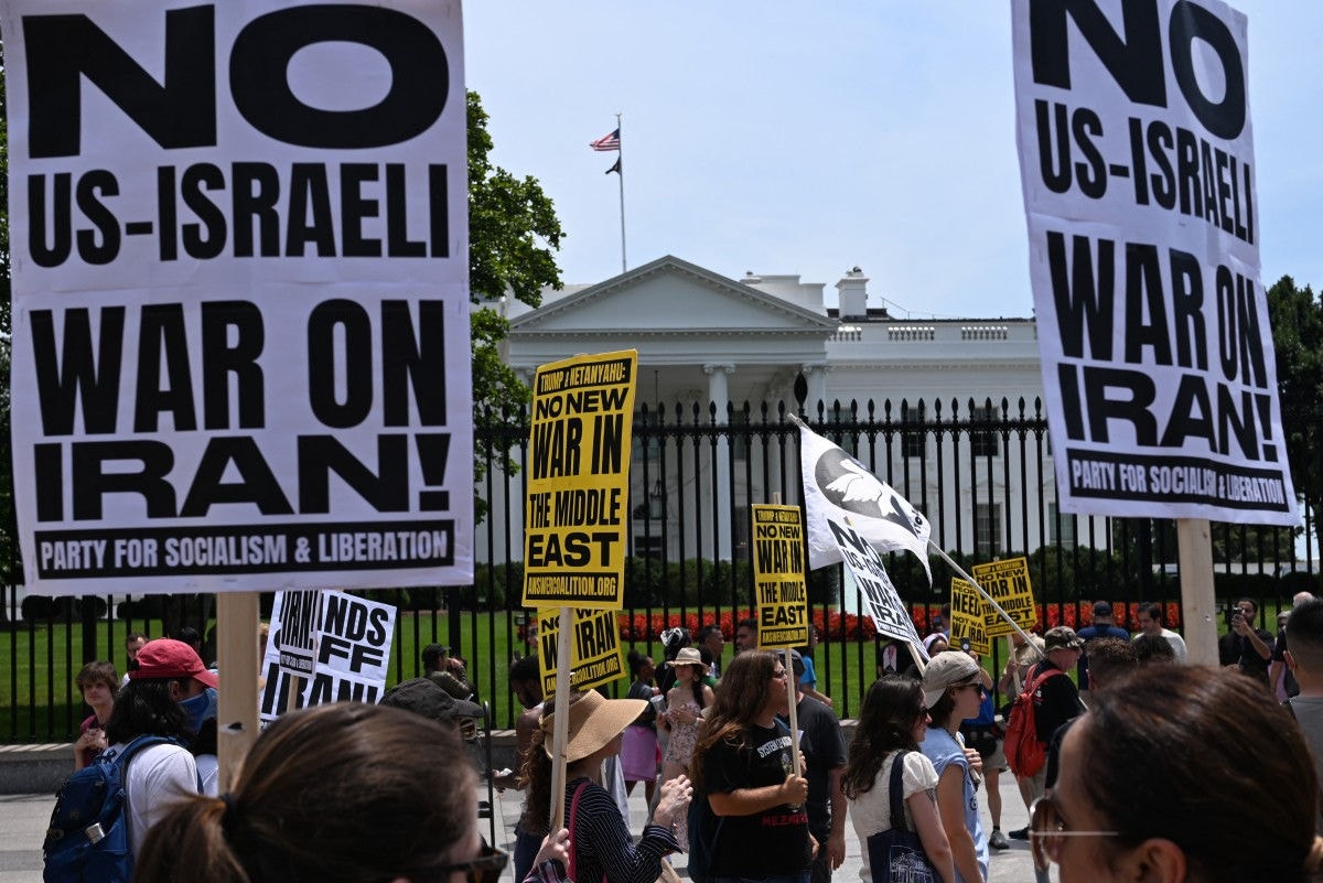 Manifestantes seguram cartazes enquanto protestam em frente à Casa Branca, em Washington, contra os ataques dos EUA às instalações nucleares iranianas