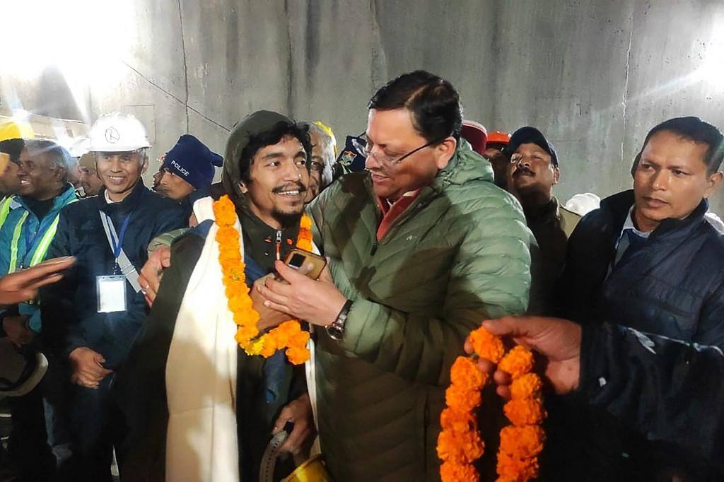 Ministro-chefe de Uttarakhand Pushkar Singh Dhami cumprimenta um dos mineiros resgatados
