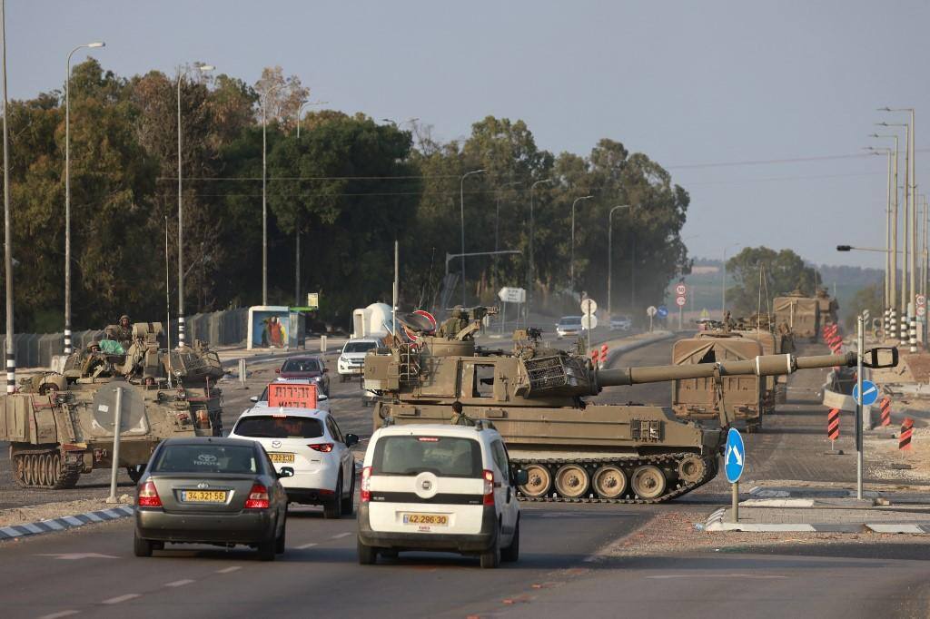 As forças israelenses cruzam uma estrada principal em seus obuses autopropulsados enquanto tropas adicionais são posicionadas perto da cidade de Sderot, no sul do país, em 8 de outubro de 2023