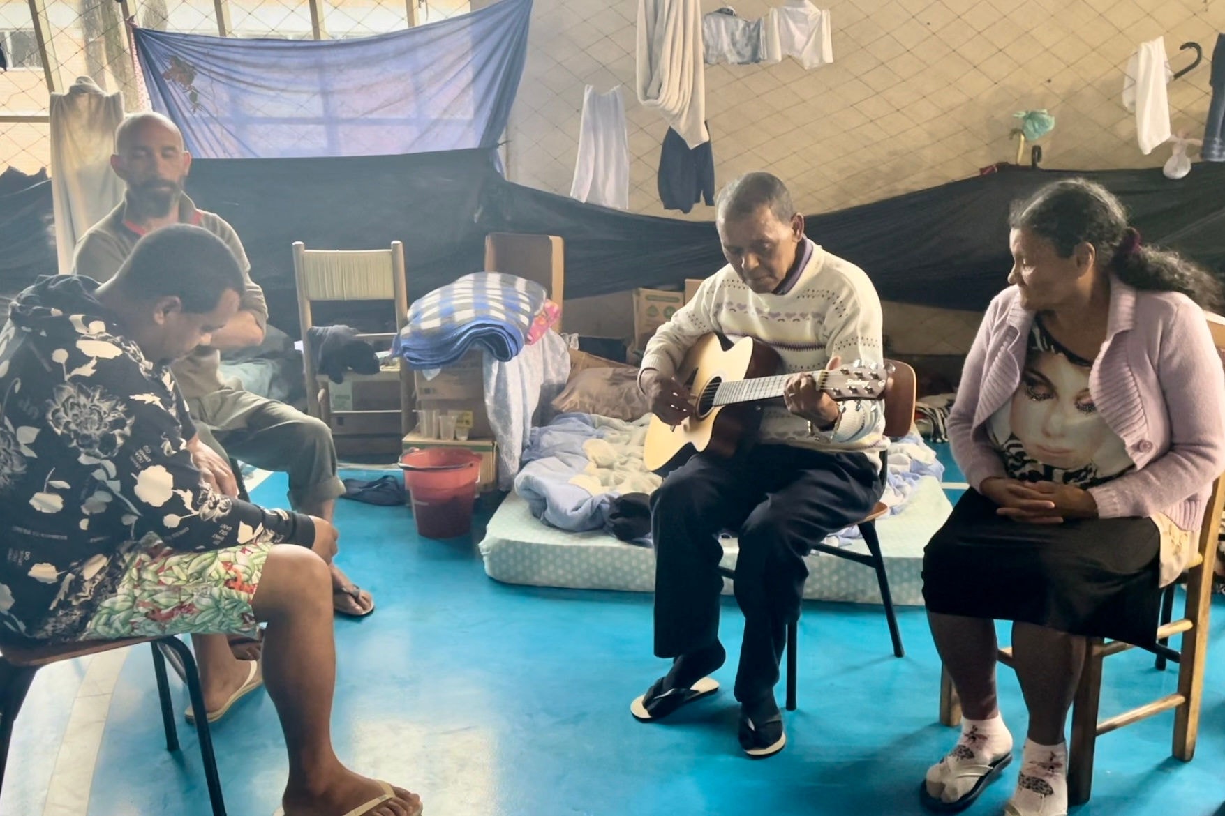 O casal Zeli e Lúcia canta ao som de um violão salvo das enchentes em Canoas, no Rio Grande do Sul