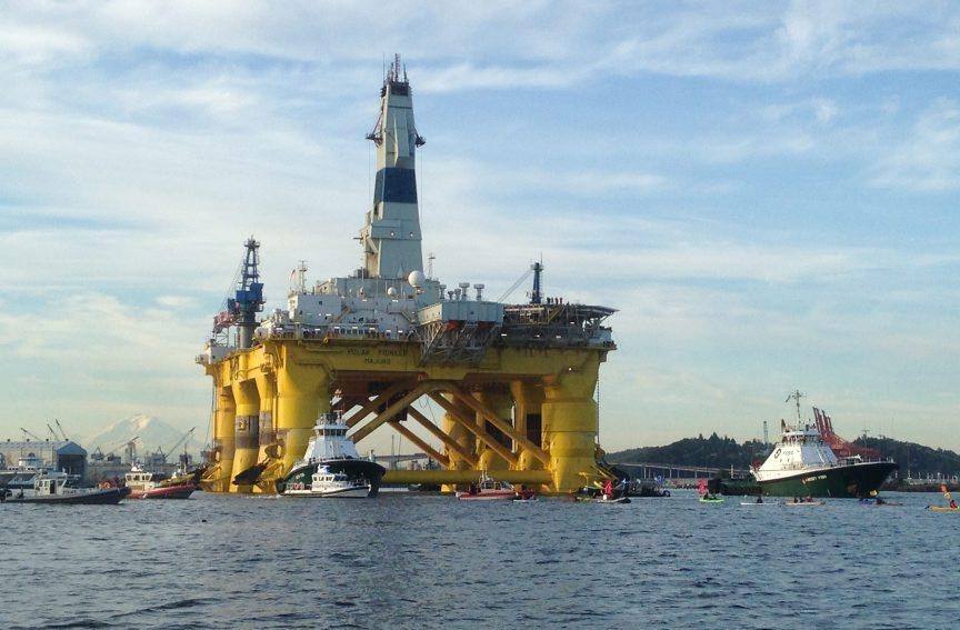 This June 15, 2015 phto shows kayakers trying to block the departure of the Shell Oil  Polar Pioneer  rig platform as it moved from Elliott Bay in Seattle, Washington.  Greenpeace activists paddling in kayaks formed a blockade Monday to keep a mammoth Shell oil rig from departing from Seattle on a mission to drill in the Arctic. Dozens of boats assembled in an arc around the towering yellow and while Polar Pioneer before dawn as tug boats were preparing to embark on the slow journey north to waters off Alaska, said John Hocevar, a Greenpeace activist who was also one of the kayakers.  AFP PHOTO / TIM EXTON