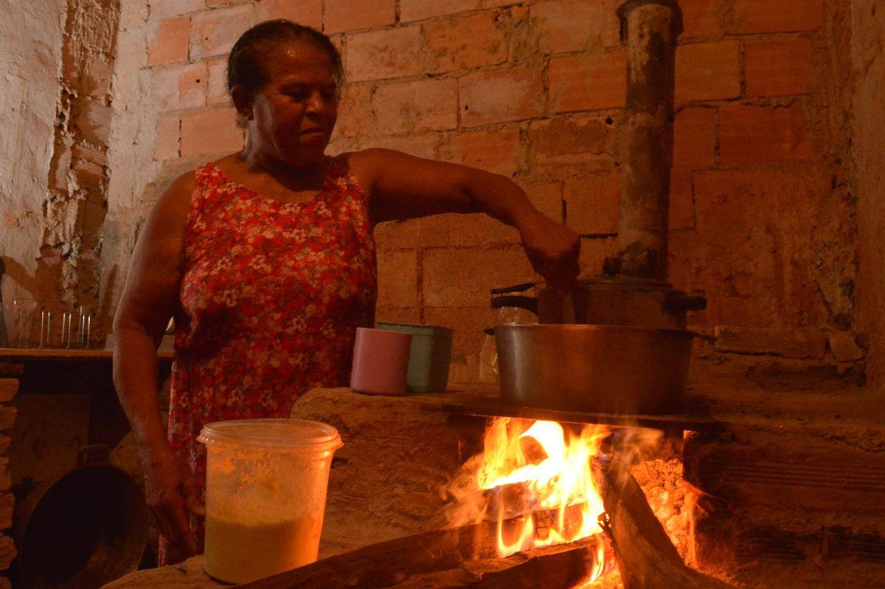 Dona Maria usa o fogão a lenha para cozinhar