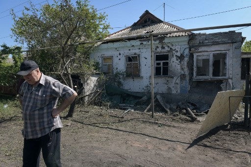 A local resident stands near a damaged house following recent shelling in Donetsk, Russian-controlled Ukraine, on May 10, 2024, amid the Russia-Ukraine conflict. (Photo by STRINGER / AFP)