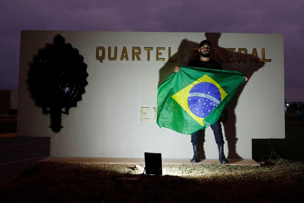 Apoiador do presidente Jair Bolsonaro exibe Bandeira do Brasil em frente ao QG do Exército, em Brasília