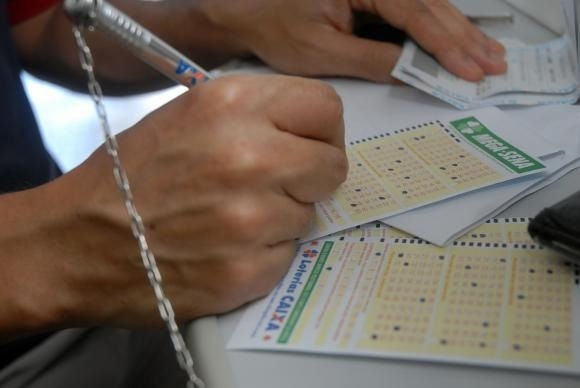 Imagem ilustrativa de uma pessoa fazendo apostas para Mega-Sena