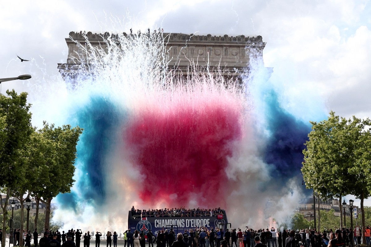 Fireworks explode as the PSG team bus parades in front of the Arc de Triomphe in Paris on June 1, 2025, a day after PSG won the 2025 UEFA Champions League final football match against Inter Milan in Munich. (Photo by Thibaud MORITZ / AFP)