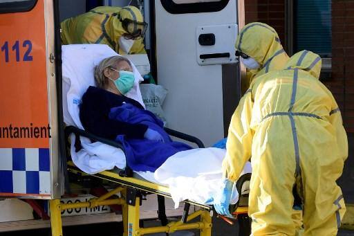 Membros da Defesa Civil carregam um paciente em uma maca quando chegam ao hospital Severo Ochoa em Leganes