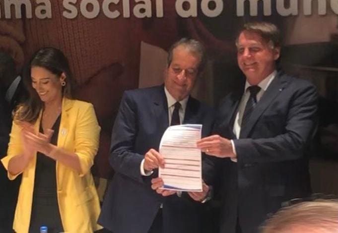O então presidente Jair Bolsonaro assina a ficha de filiação do Partido Liberal (PL) ao lado do presidente da sigla, Valdemar da Costa Neto, e da ministra Flávia Arruda