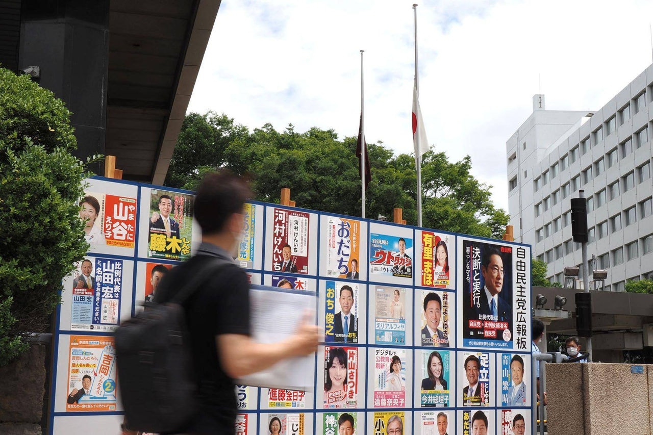 Cartazes de campanha de candidatos do Partido Liberal Democrático na eleição da câmara alta, enquanto a bandeira do Japão e a do LDP estão a meio mastro, em Tóquio