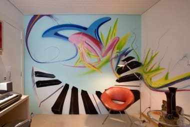 Neste ambiente, o grafite envolve os usuários da sala e preenche a decoração