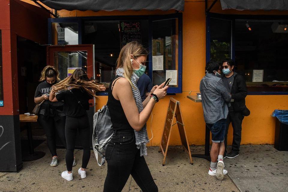 Pessoas transitam com máscaras no East Village: cidade de Nova York está em sua nona semana de bloqueio e diretrizes