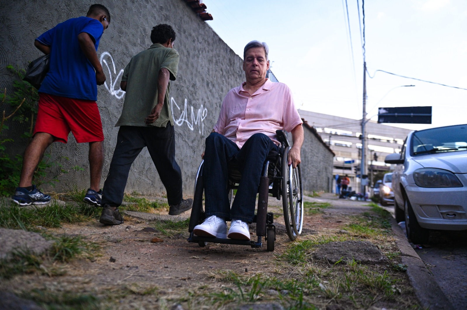 Leonardo, cadeirante, tenta transitar por uma calçada com piso irregular e sem rampa em BH