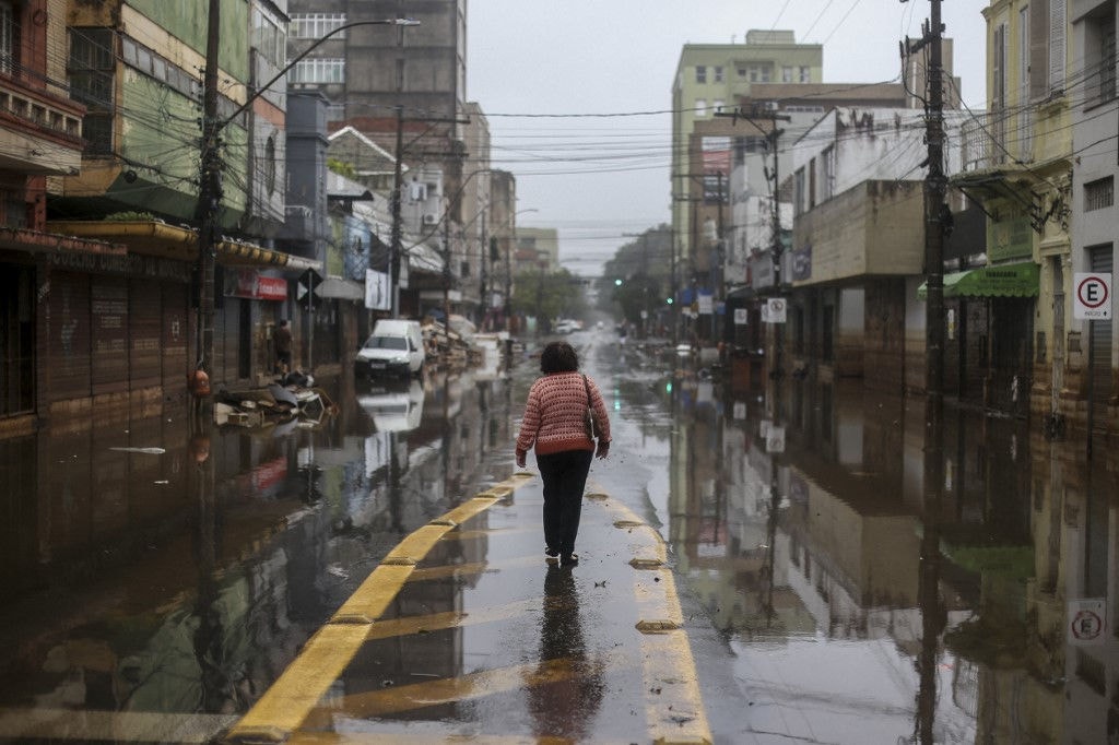 Mulher caminha por rua alagada do centro de Porto Alegre, um mês após início das enchentes que assolam o Rio Grande do Sul