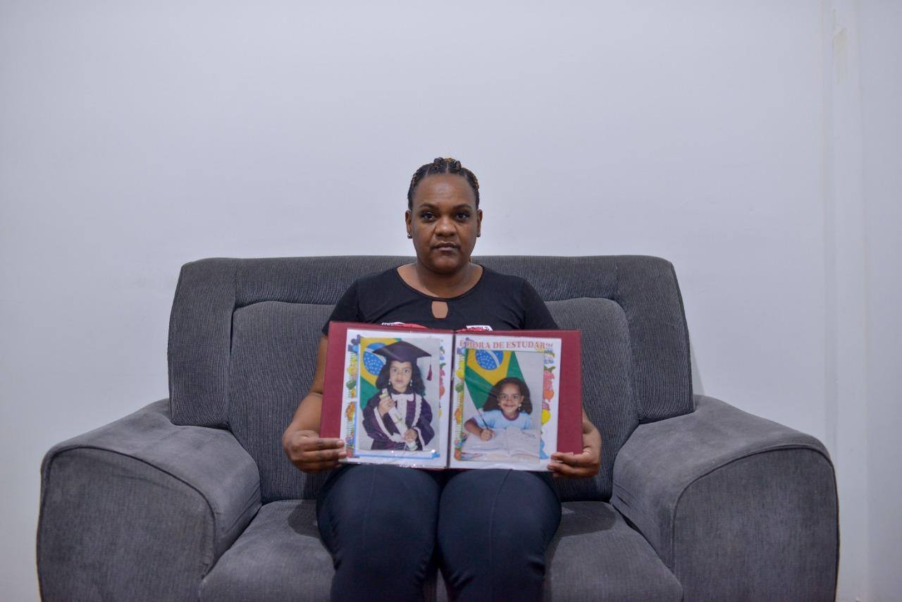 Imagem mostra mãe segurando foto da filha assassinada