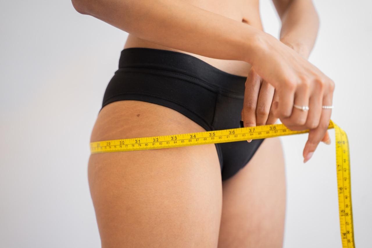 Mulher usando uma fita métrica para irar medidas do próprio corpo