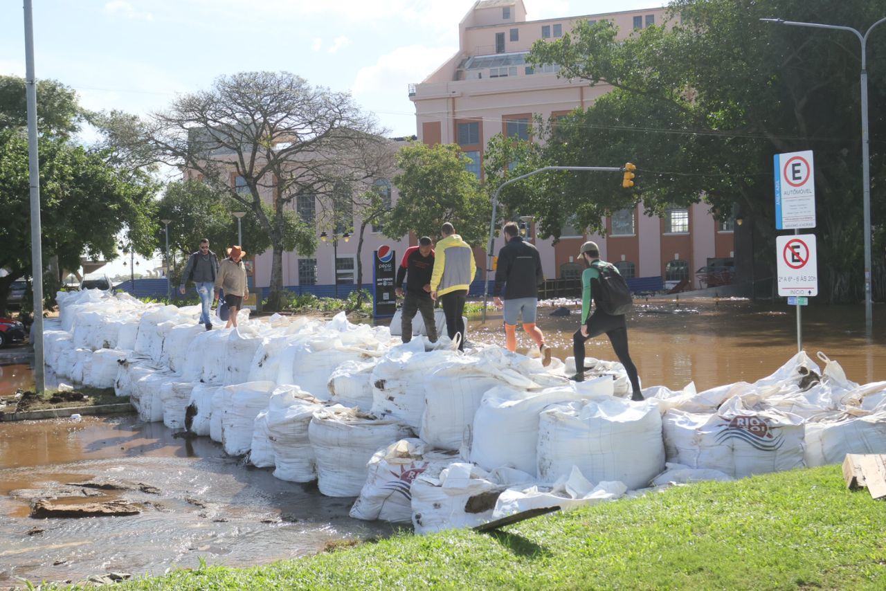 Pedestres passam por cima de sacos de areia na região do Cais do Porto, em Porto Alegre