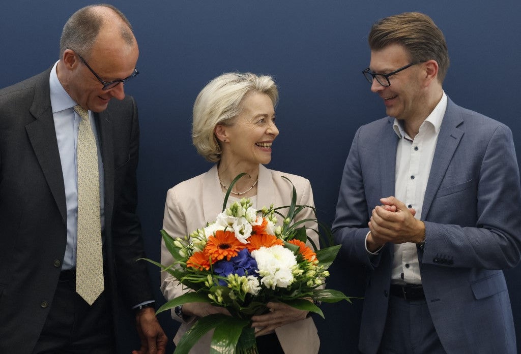 European Commission President Ursula von der Leyen (C) holds a bouquet of flowers as she stands between Friedrich Merz (L), leader of Germany's conservative Christian Democratic Union (CDU), and the leader of the conservative CDU/CSU group at the European Parliament Daniel Caspary at the start of a CDU leadership meeting at the CDU headquarters in Berlin on June 10, 2024, one day after European Parliament elections. (Photo by Odd ANDERSEN / AFP)